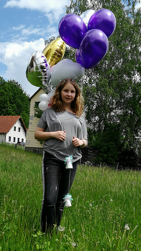 A girl Melanie, a CI cochlear user, with baloons in the garden
